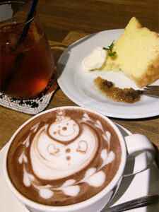 雪だるまのラテアートが施されたココアとアイスティーとシフォンケーキ。