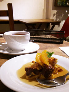 オレンジが乗ったデザートと紅茶が入ったカップアンドソーサー。